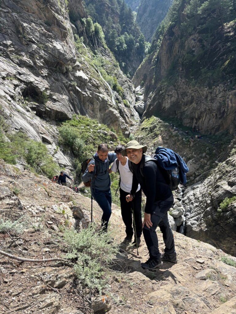 Trekkers navigating rocky mountain path on Kinner Kailash trail